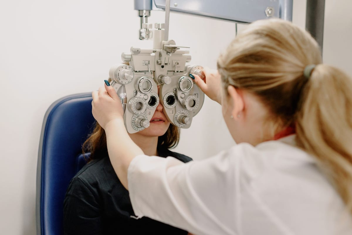 An optometrist adjusting a phoropter during an eye exam