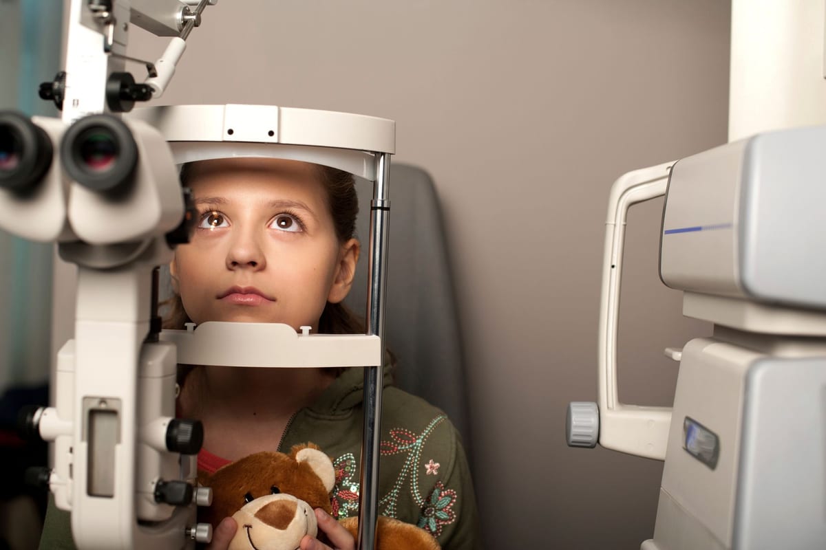 A child having her eyes checked at a slit lamp